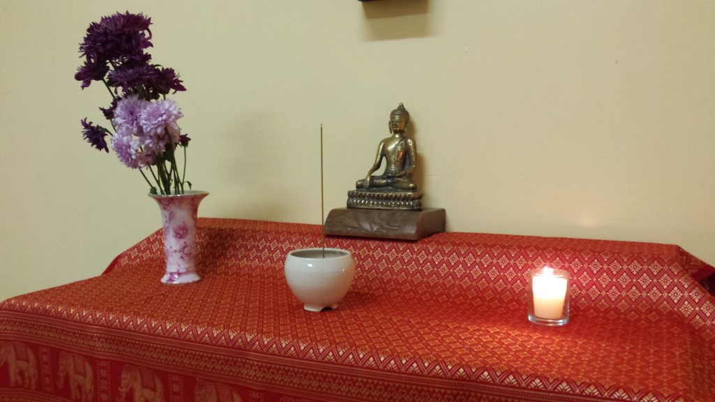 A Buddhist altar with Buddha statue, flowers, incense burner and candle, set up in St. James Episcopal church in San Francisco, CA.
